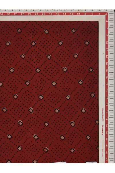 A close-up of a red patterned fabric with a repeating small diamond and dot motif, shown flat with measurement rulers along the top and right edges.